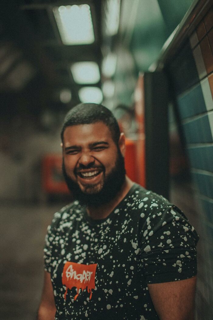 Man with a beard laughing during a night shift in a dimly lit corridor, reflecting 3 AM chaos at work.