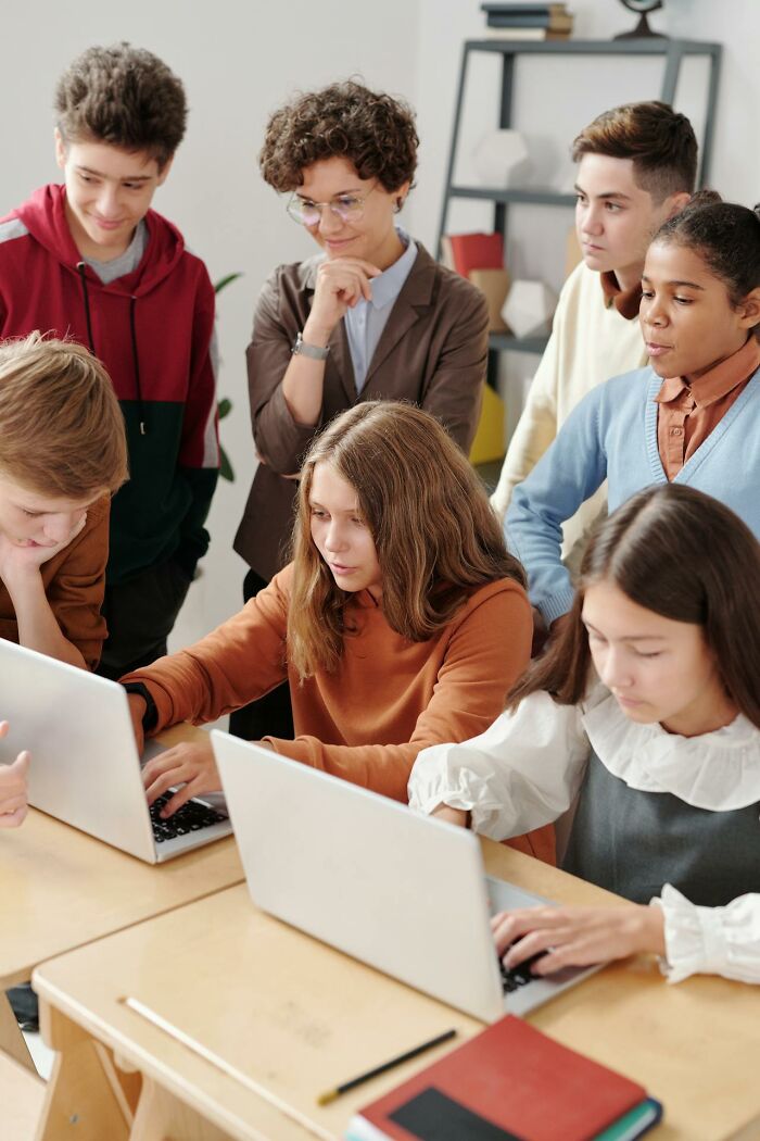 Students and teacher working on laptops in classroom, creepiest displays of intelligence.