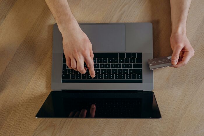 Person holding credit card and typing on laptop keyboard, illustrating rich people out of pocket statements.