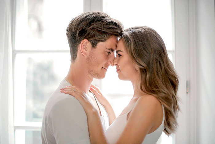 Young couple embracing by window, tender intimate moment, mom regrets becoming a parent theme