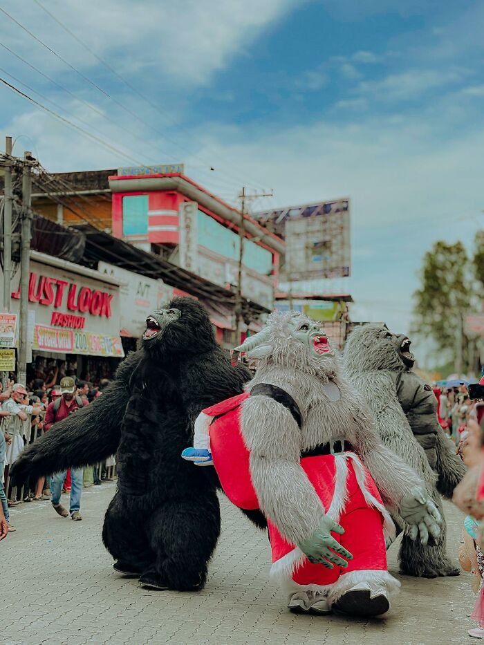 People in large animal and monster costumes walking in a street parade, capturing 3 AM chaos during the night shift.