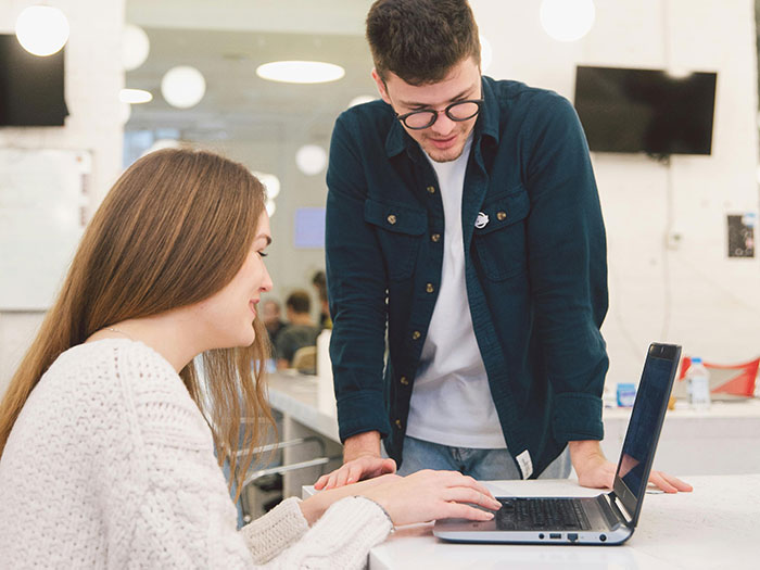 Woman puts coworker on blast on social media, shocked reaction in office setting with laptop and casual attire