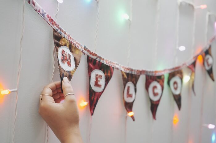 Hand adjusting colorful welcome banner with string lights on wall, symbolizing surprises after getting out of prison