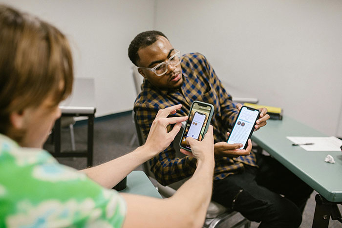 Two students in a classroom discussing phone use and rules after professor enforces phone policy without prior warning.