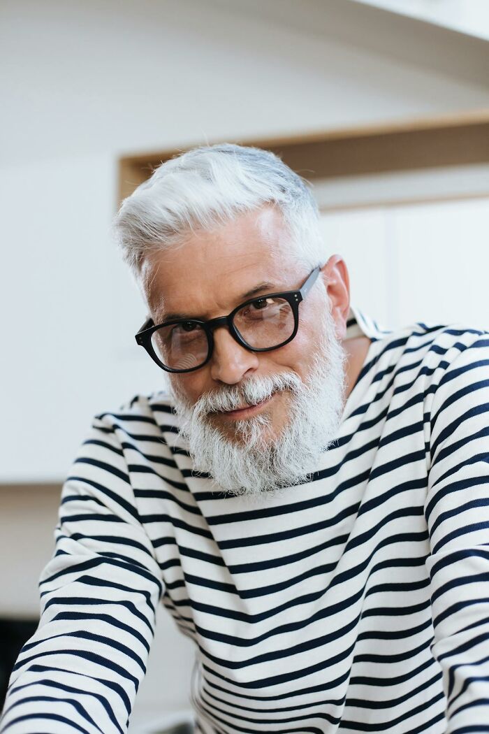 Older man with gray hair and beard, wearing glasses and striped shirt, reflecting on things that shocked people after prison.