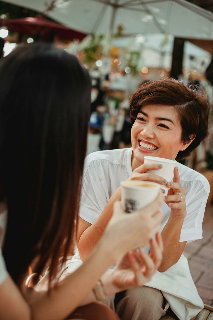 Woman laughing with friend over coffee outdoors, It Rained Frogs