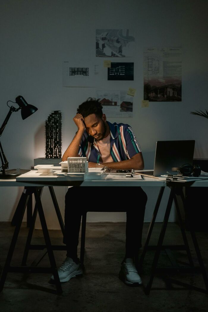 Tired worker experiencing 3 AM chaos during the night shift, overwhelmed with tasks at a dimly lit desk.