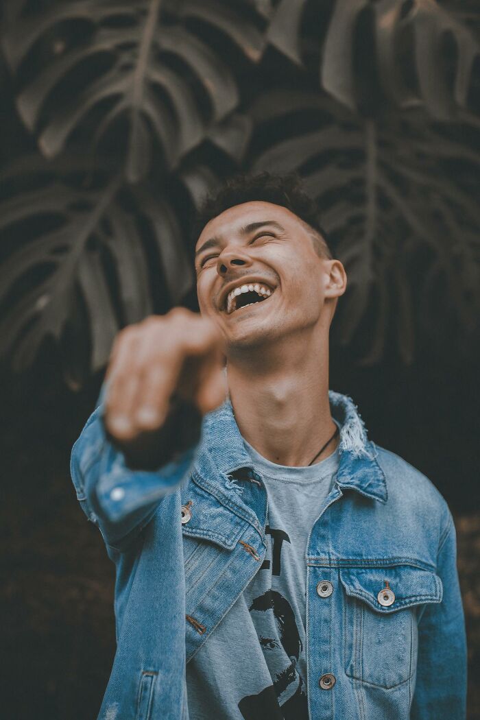 Young man laughing and pointing in denim jacket, representing creepiest displays of intelligence