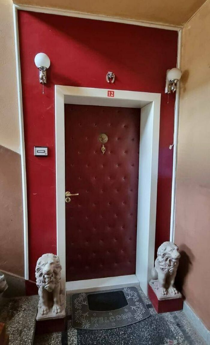 Padded door with lion statues and welcome mat in an Eastern European apartment hallway.