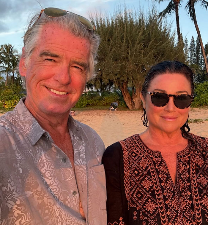 Pierce Brosnan and his wife outdoors at sunset, wife wearing sunglasses, highlighting transformation and online troll attacks.