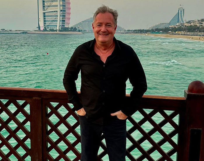 Piers Morgan standing by the waterfront in Dubai, smiling, relating to incident involving Donald Trump and serious injury. Piers Morgan standing by the waterfront in Dubai, smiling, relating to incident involving Donald Trump and serious injury.