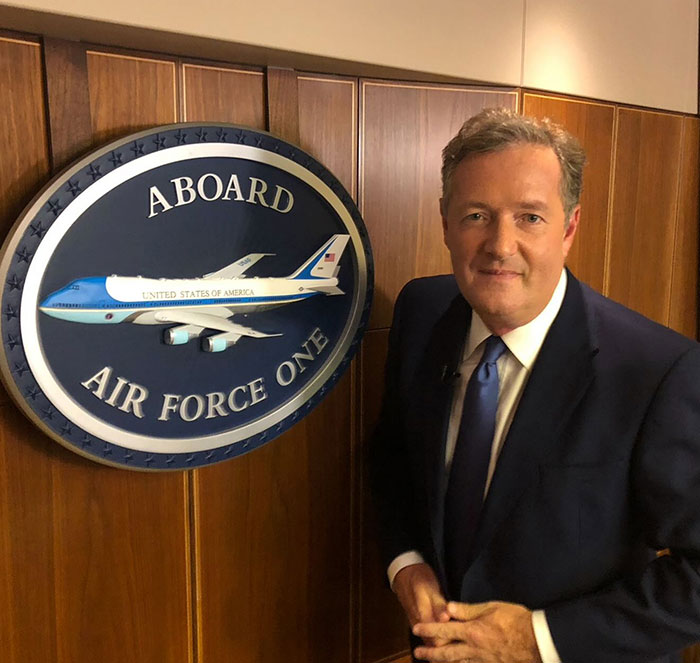 Piers Morgan standing beside Air Force One sign, relating to Donald Trump and serious injury incident. Piers Morgan standing beside Air Force One sign, relating to Donald Trump and serious injury incident.