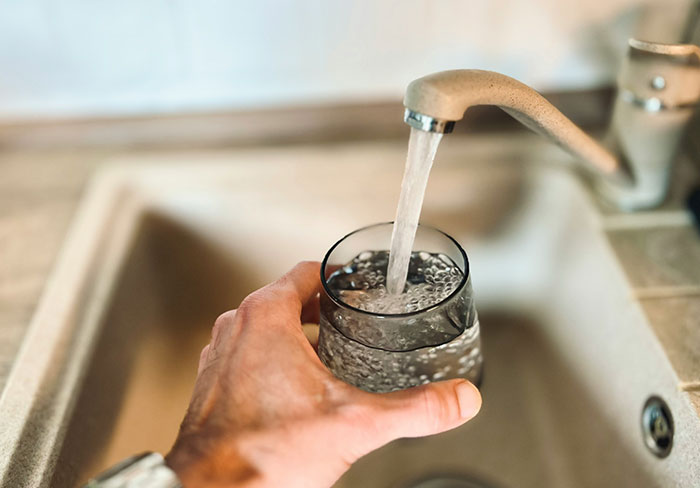 Hand filling a glass with water from kitchen faucet, illustrating insights professionals share about their jobs.