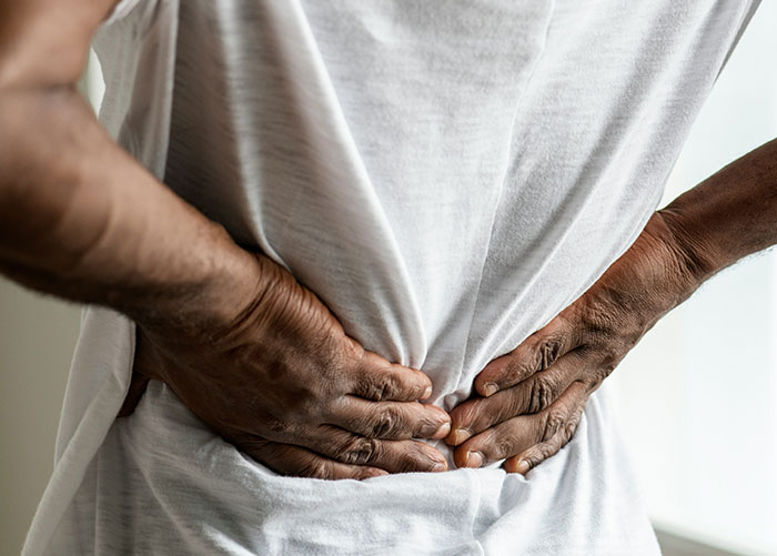 Person holding lower back in pain, illustrating what professionals want the general public to know about their jobs.