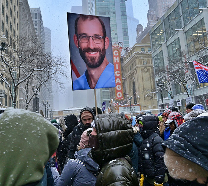 Crowd in snowy Chicago holding a large portrait, reflecting heated debate and protests related to ICE and Michael Che on SNL. Crowd in snowy Chicago holding a large portrait, reflecting heated debate and protests related to ICE and Michael Che on SNL.