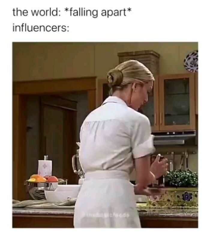 Woman in white dress preparing food in kitchen with caption about world falling apart and influencers, funny memes concept.