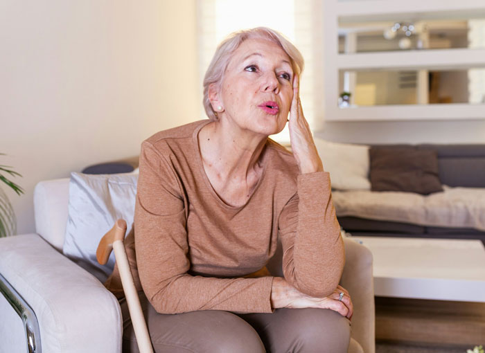 Older woman sitting on a chair looking frustrated in a living room, representing MIL thinking she won against DIL.
