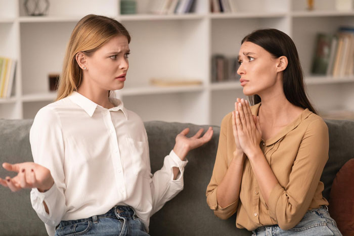 Two women on a couch in disagreement, one refusing to give food while the other pleads, showing emotional tension. Two women on a couch in disagreement, one refusing to give food while the other pleads, showing emotional tension.