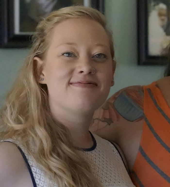 Woman with long blonde hair and nose ring smiling softly in a casual indoor setting, related to Minneapolis ICE agent story.
