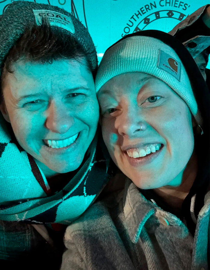 Two people smiling closely together wearing winter hats and jackets, related to Renee Good’s wife and fatal ICE incident. Two people smiling closely together wearing winter hats and jackets, related to Renee Good’s wife and fatal ICE incident.