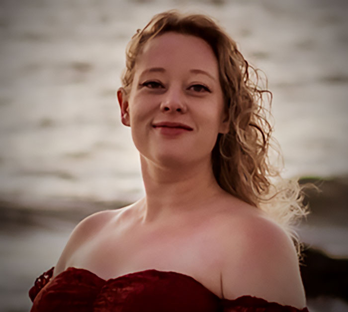 Woman with curly hair smiling warmly by the water, representing Minneapolis ICE agent crowdfunding hero story.
