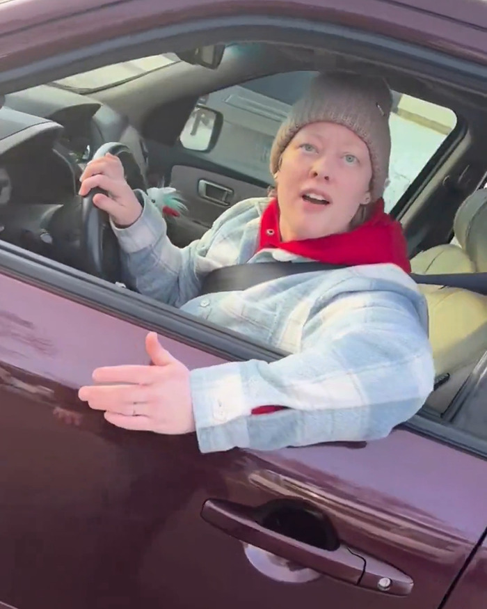 Person in a car wearing a beanie and red hoodie with arm extended, related to newly released ICE video context. Person in a car wearing a beanie and red hoodie with arm extended, related to newly released ICE video context.