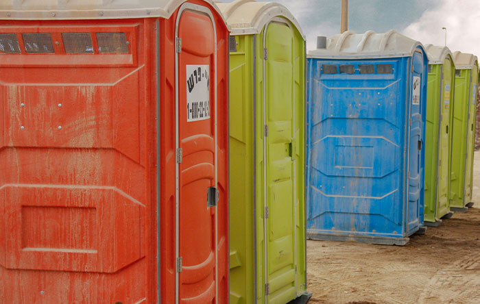 Colorful portable toilets lined up outdoors, symbolizing humorous revenge moments and people getting the last laugh.