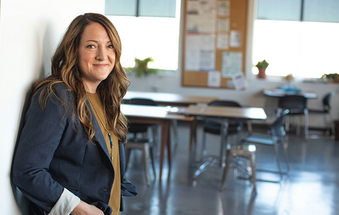 Woman smiling confidently in an office setting, representing people who got the last laugh by delivering glorious revenge.