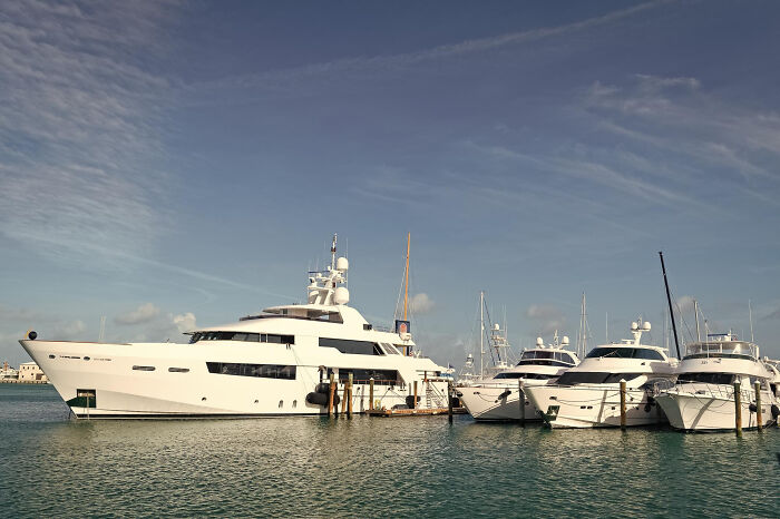 Luxury yachts docked at a marina under a clear sky, illustrating lifestyles of rich people and 1% norms.