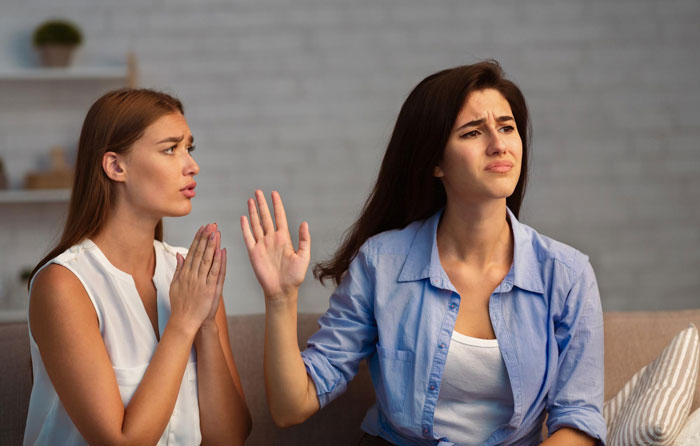 Two women having a tense conversation on a couch, portraying roommate boyfriend vacation drama emotions. Two women having a tense conversation on a couch, portraying roommate boyfriend vacation drama emotions.