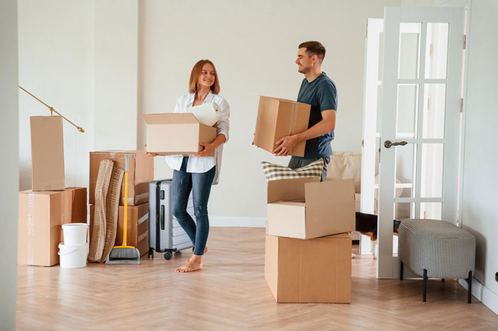 Young man and woman carrying boxes while moving in, capturing a roommate and girlfriend moment during unpacking. Young man and woman carrying boxes while moving in, capturing a roommate and girlfriend moment during unpacking.