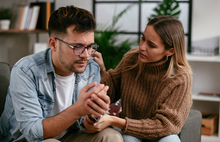 A woman comforting a distressed man in a living room, illustrating the impact of ruining family relationship lying MIL issues. A woman comforting a distressed man in a living room, illustrating the impact of ruining family relationship lying MIL issues.