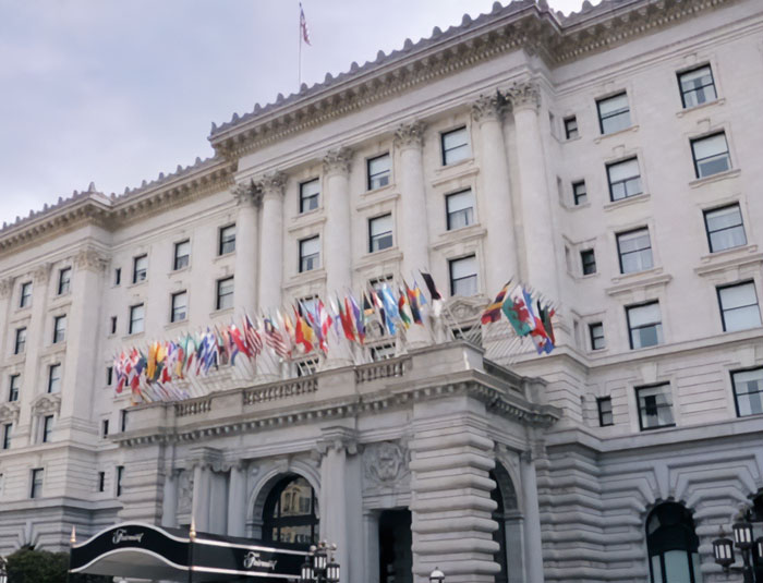 Historic San Francisco hotel exterior with multiple international flags, linked to horrifying new twist in Tommy Lee Jones's daughter case.
