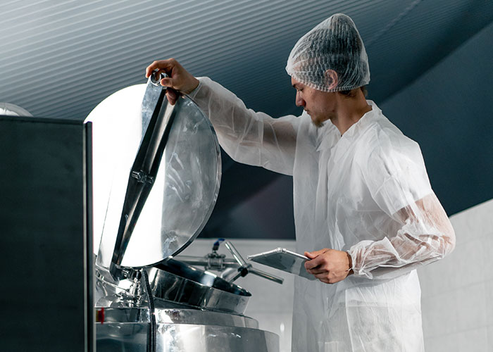 Worker in protective clothing opening industrial equipment, illustrating terrifying close calls in a controlled environment.