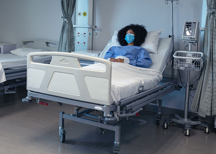 Patient recovering in hospital bed wearing mask after terrifying close calls, reflecting on survival and safety.