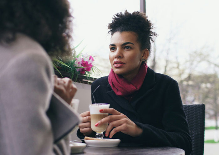 Two women having an intense conversation over coffee, representing people anonymously sharing explosive secrets.