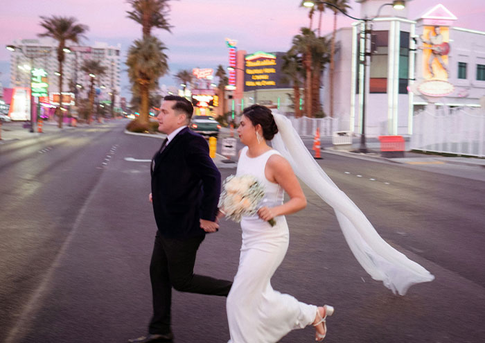 Bride and groom running across street at sunset, capturing a candid moment in an urban setting for explosive secrets content.