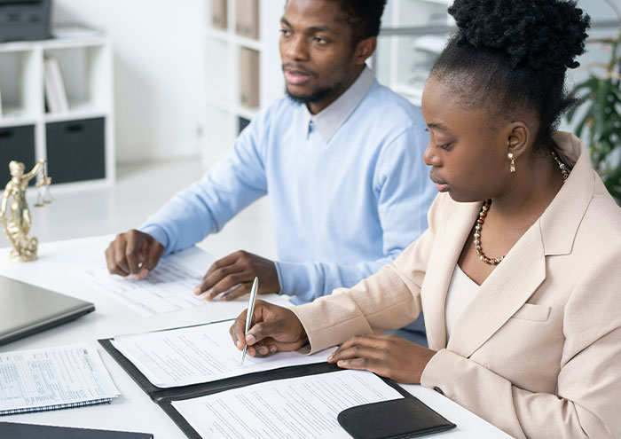 Two professionals reviewing documents at a desk, illustrating people anonymously sharing explosive secrets.