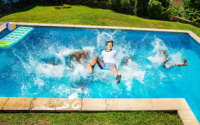Children jumping into a pool creating big splashes, capturing a moment that security guards replay as weird camera footage.