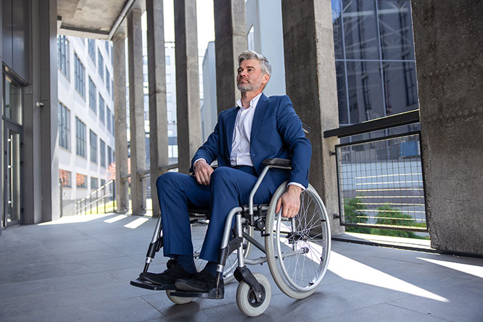 Mature security guard in a wheelchair outside an office building reviewing weird camera footage 