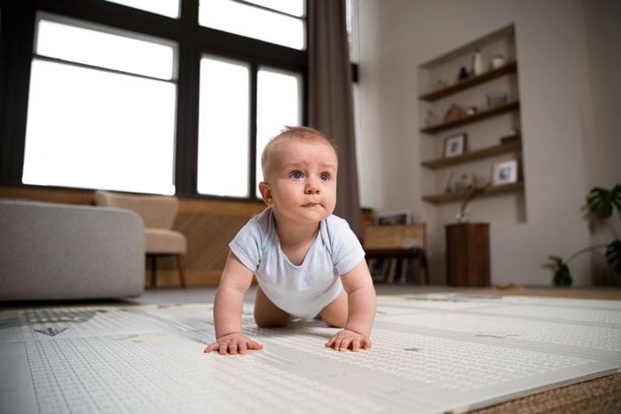 Toddler crawling on a play mat in a living room, highlighting concerns of mom's neglect and CPS involvement.