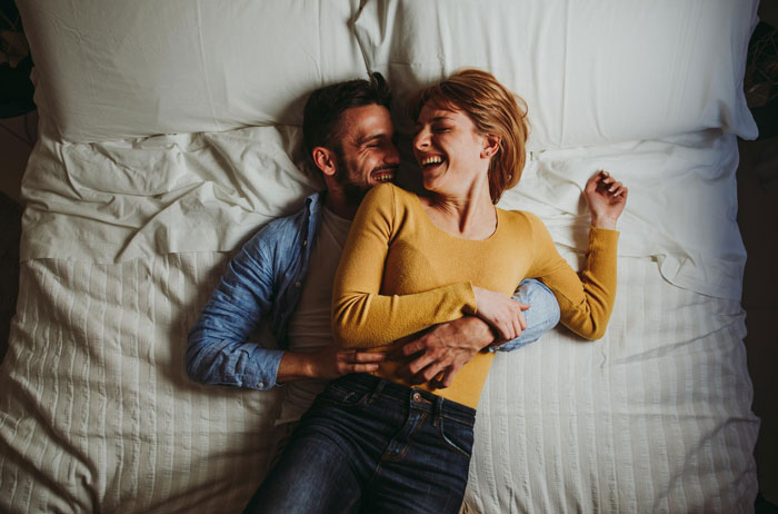 Couple laughing and hugging on a bed, illustrating family and emotional connection despite underlying neglect issues. Couple laughing and hugging on a bed, illustrating family and emotional connection despite underlying neglect issues.