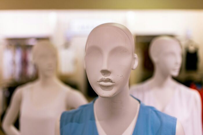 Three faceless mannequins in a clothing store showcasing outfits, illustrating weird public displays without shame.