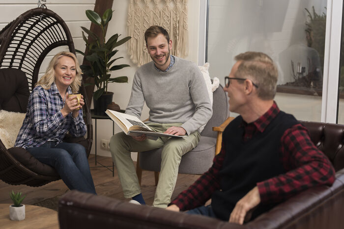 Mom inviting son&rsquo;s girlfriend to dad&rsquo;s party, family sitting and talking in cozy living room setting.