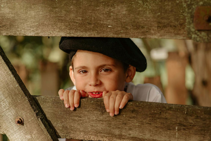 Young boy climbing wooden fence, wearing a black hat, illustrating concerns about privacy and family boundaries.