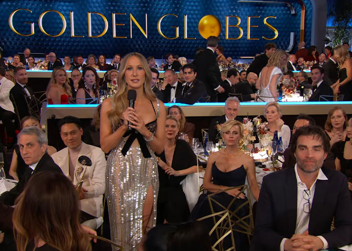 Host speaking on stage at the 2026 Golden Globes amid a crowd of attendees capturing awkward moments fans found cringeworthy.