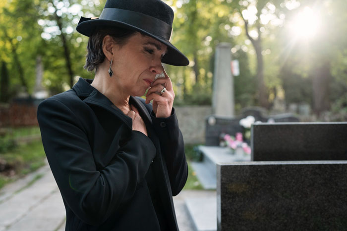 Woman mourning at a gravesite, expressing grief and loss, symbolizing the step kids mom loss money theme. Woman mourning at a gravesite, expressing grief and loss, symbolizing the step kids mom loss money theme.