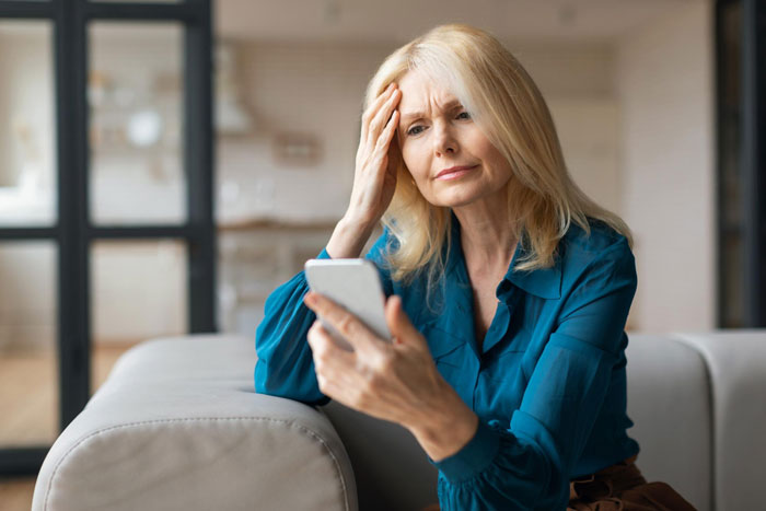 Woman looking worried while checking her phone, reflecting concerns about step kids and money loss issues. Woman looking worried while checking her phone, reflecting concerns about step kids and money loss issues.