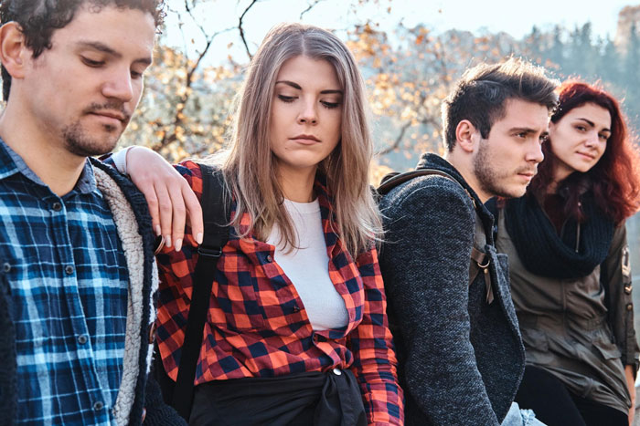 A step-kids mom looking upset and distant while standing outdoors with three young adults during autumn. A step-kids mom looking upset and distant while standing outdoors with three young adults during autumn.