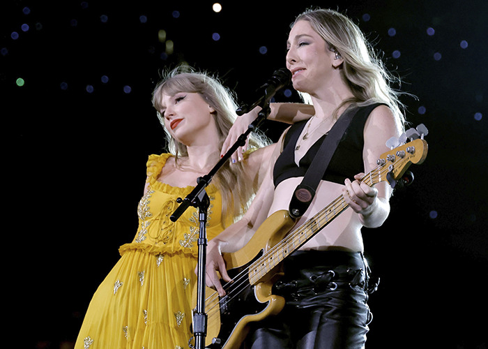 Taylor Swift in a yellow dress performing on stage with a bassist, fans scrutinizing her wedding look choices Taylor Swift in a yellow dress performing on stage with a bassist, fans scrutinizing her wedding look choices